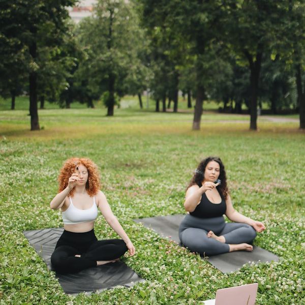 A group of people practicing yoga outdoors in a park.