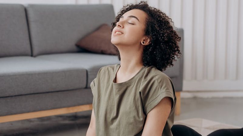 Person meditating peacefully during a yoga session with green light.