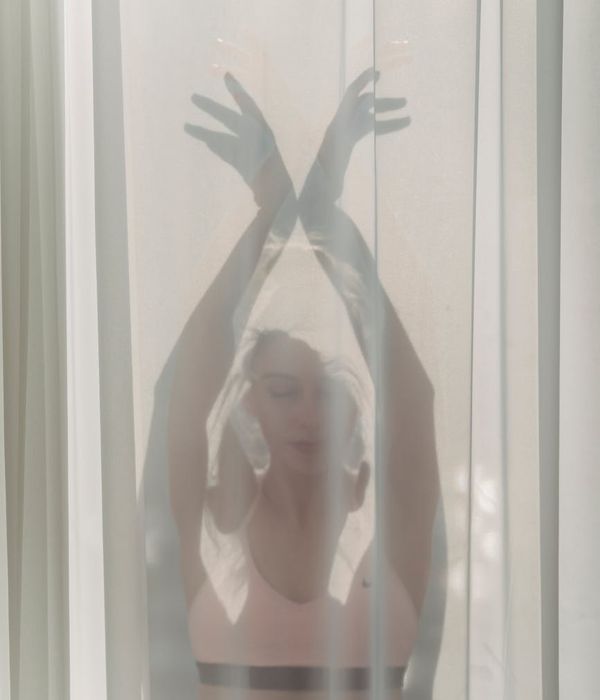 Woman in a graceful yoga pose, illuminated by gentle light.